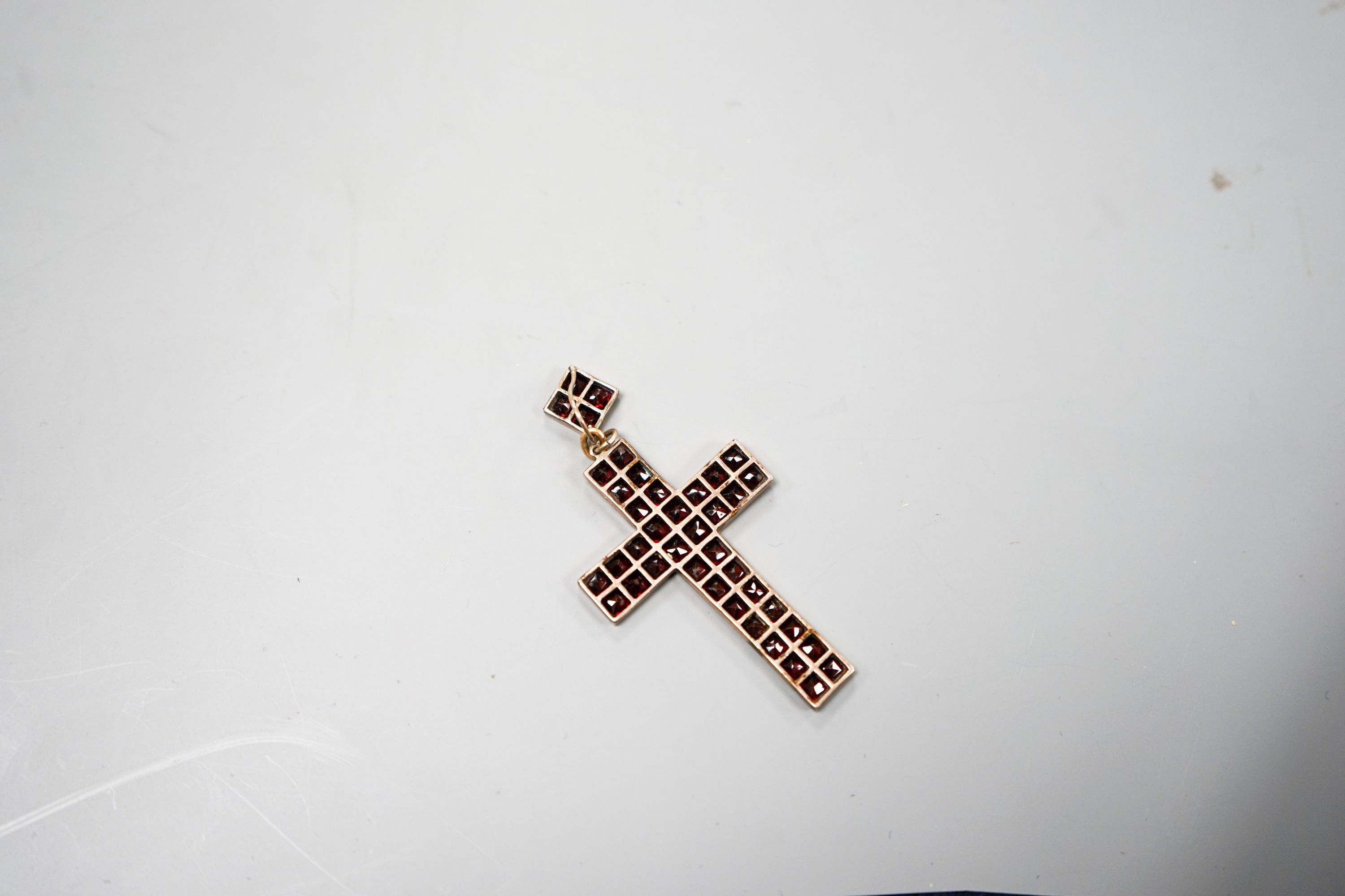 A yellow metal and pave set garnet cross pendant, overall 69mm, gross weight 6.7 grams.